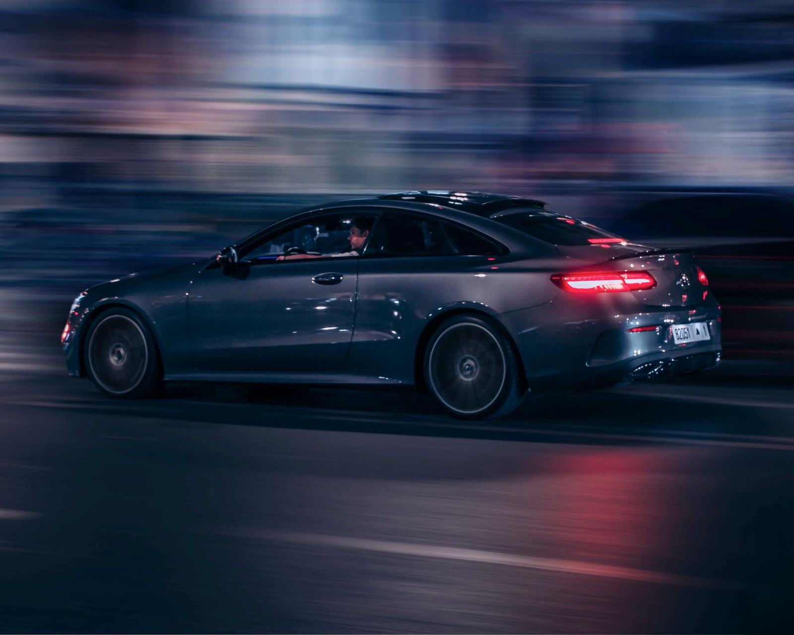 Grey Mercedes coupe at speed with red light trails