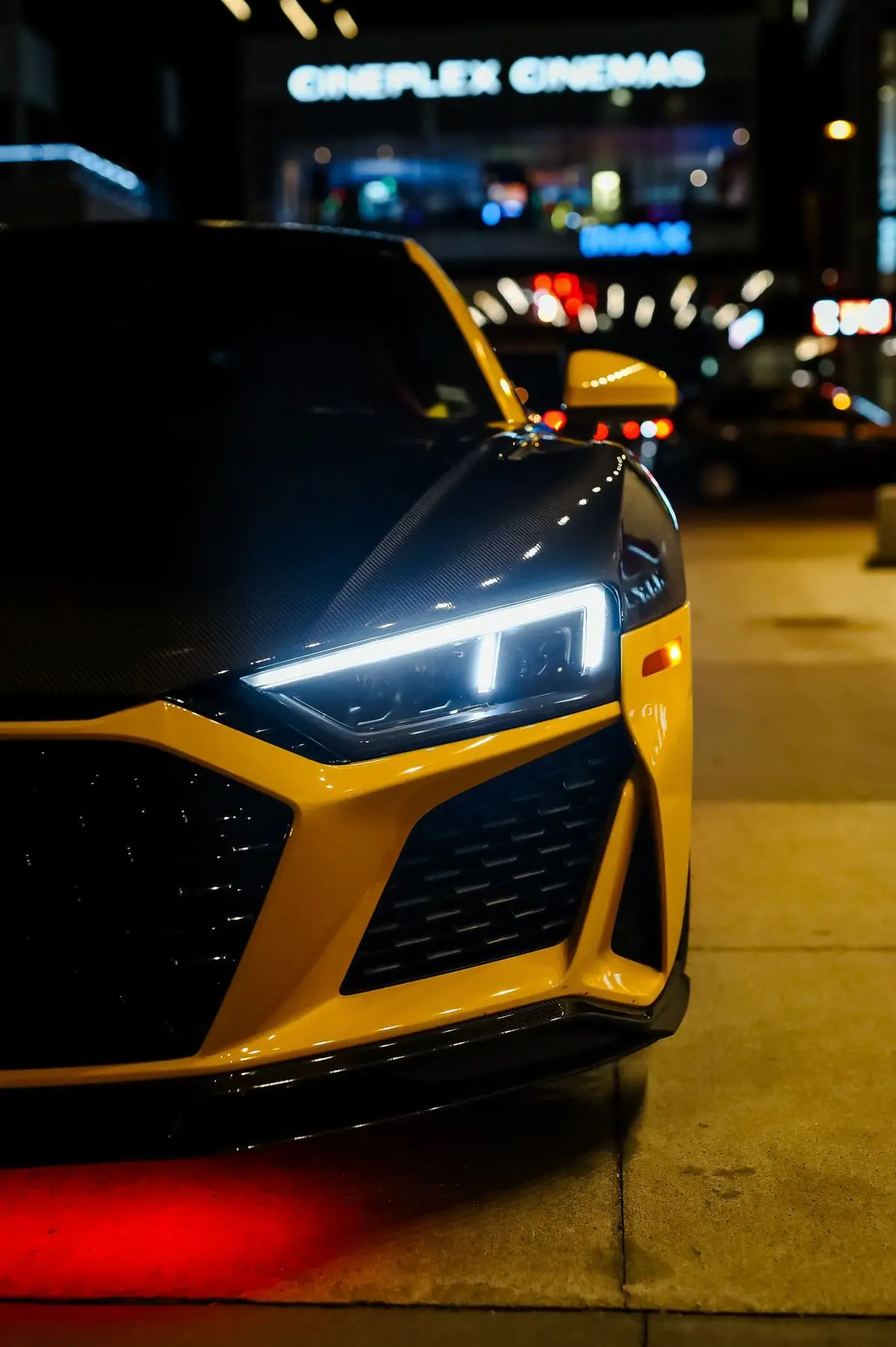 Yellow Audi R8 at night outside a cinema